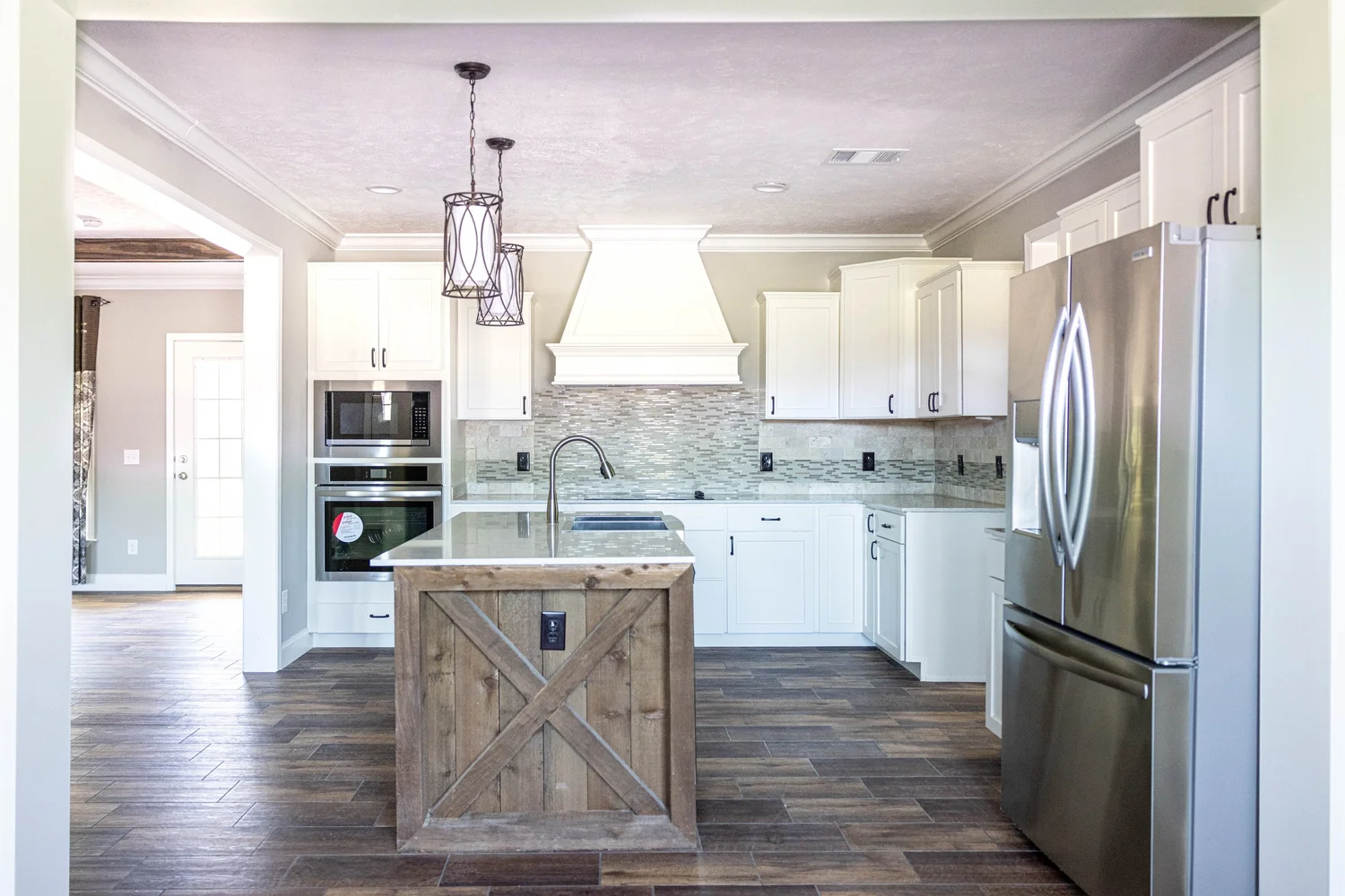 Modern kitchen with white cabinets, stainless steel appliances, and a rustic wood island. Two pendant lights hang above. Warm, inviting atmosphere.