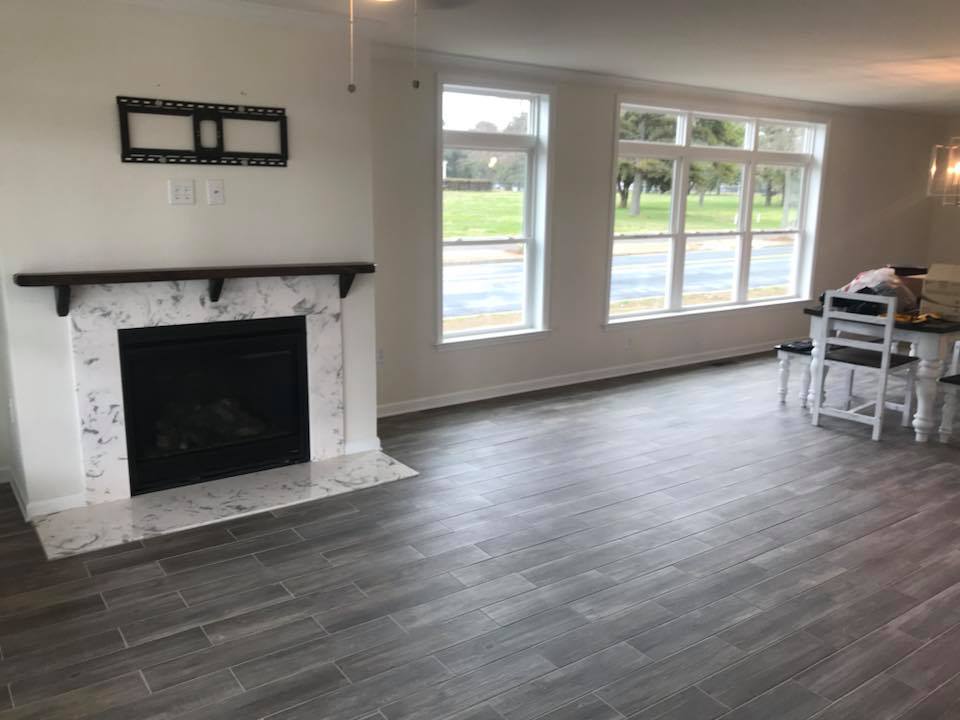 Spacious, modern living room with a tiled fireplace on the left, large windows offering park views, and a dining table on wooden floors. Bright and airy.