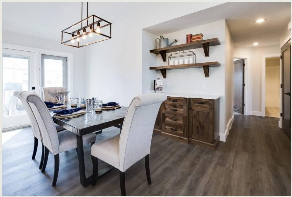 Modern dining room with a marble table set for four, featuring beige upholstered chairs. Wooden shelves and sideboard on the right, creating a cozy, welcoming ambiance.