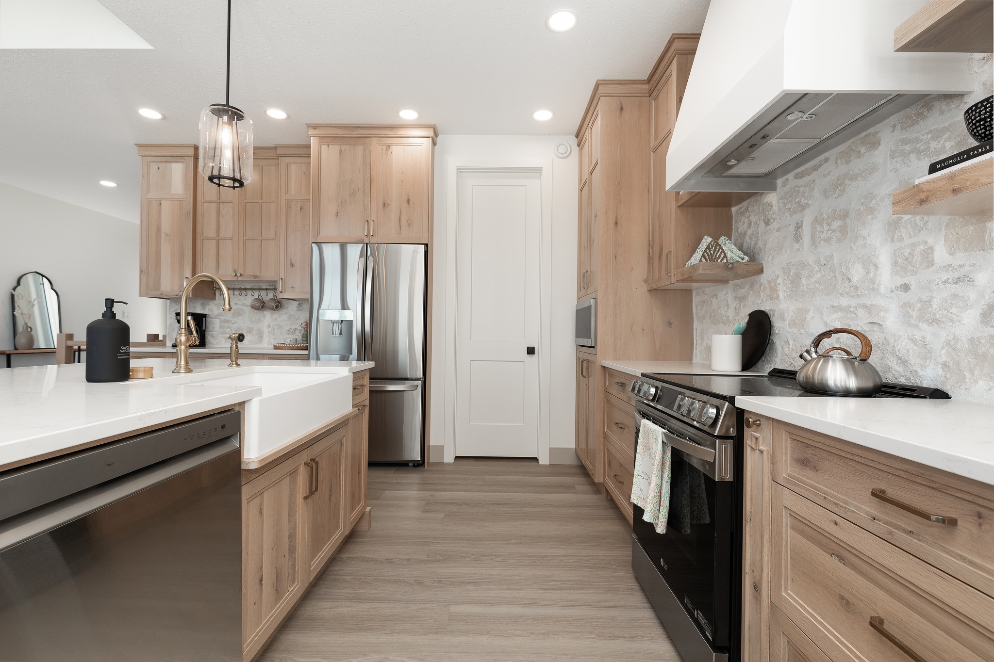 Sleek modern kitchen with wooden cabinets, stainless steel appliances, and white stone countertops. Bright, airy feel with stylish pendant lighting.