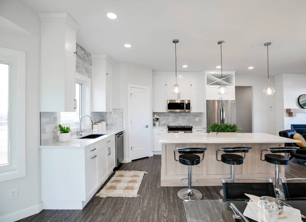 A modern kitchen featuring white cabinets and sleek black stools around a central island.
