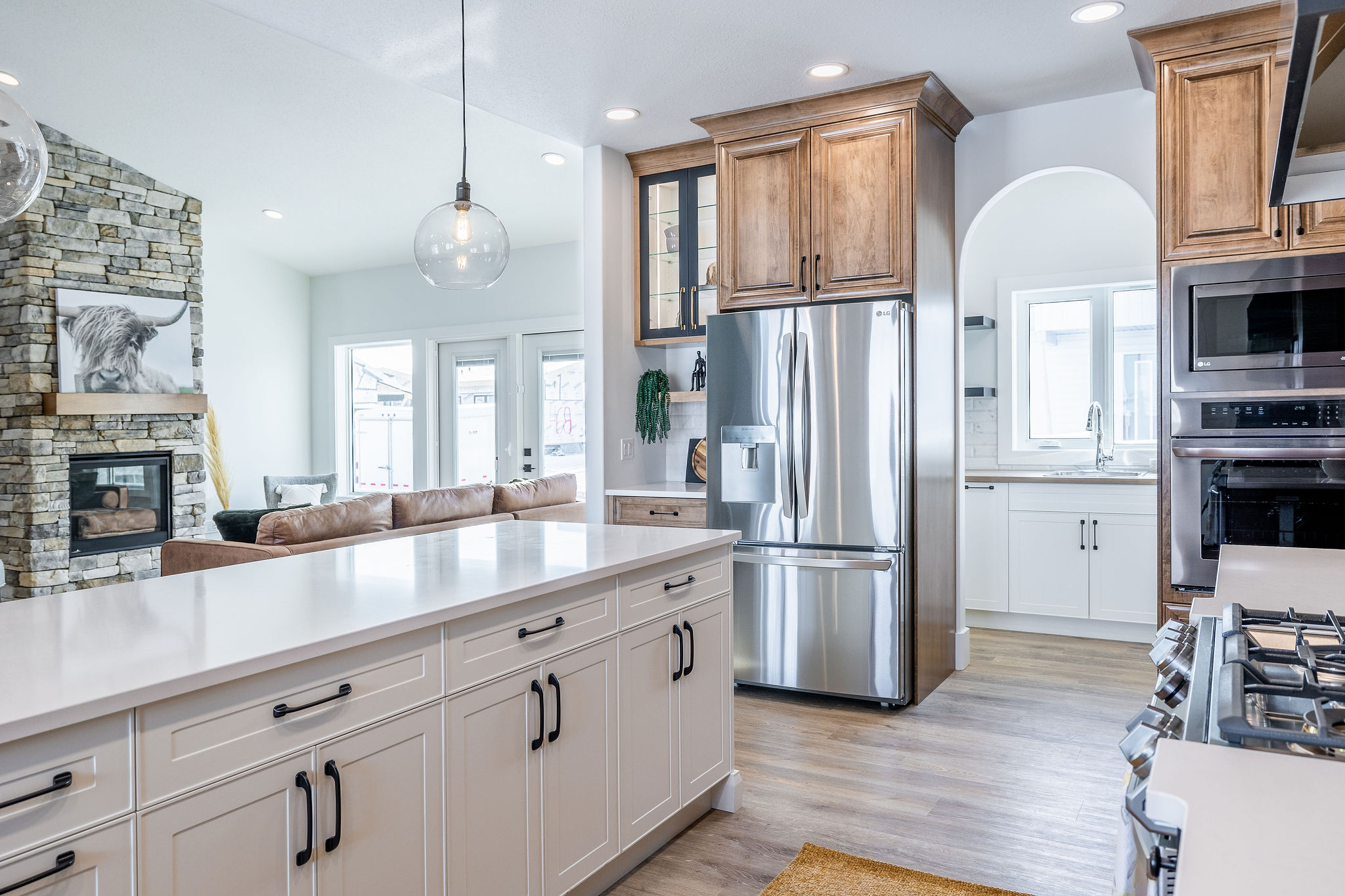 Modern kitchen with white cabinets, stainless steel appliances, and wooden accents. A bright, airy space with a stone fireplace and comfortable seating.