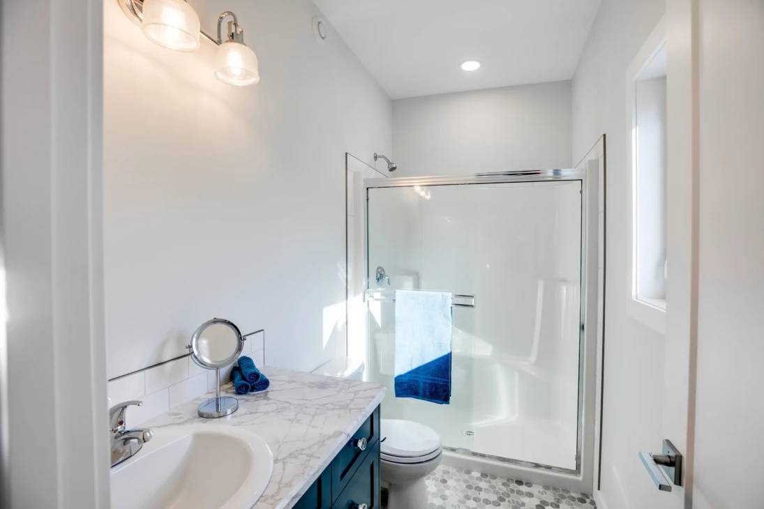 A bathroom featuring a shower stall and a sink, with neutral-colored tiles and modern fixtures.