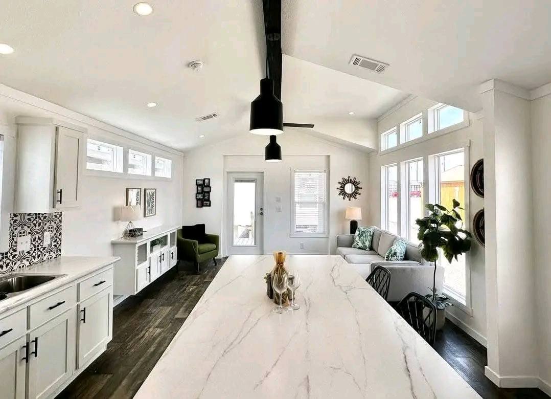 A modern kitchen featuring a sleek marble island and a stylish ceiling fan overhead.