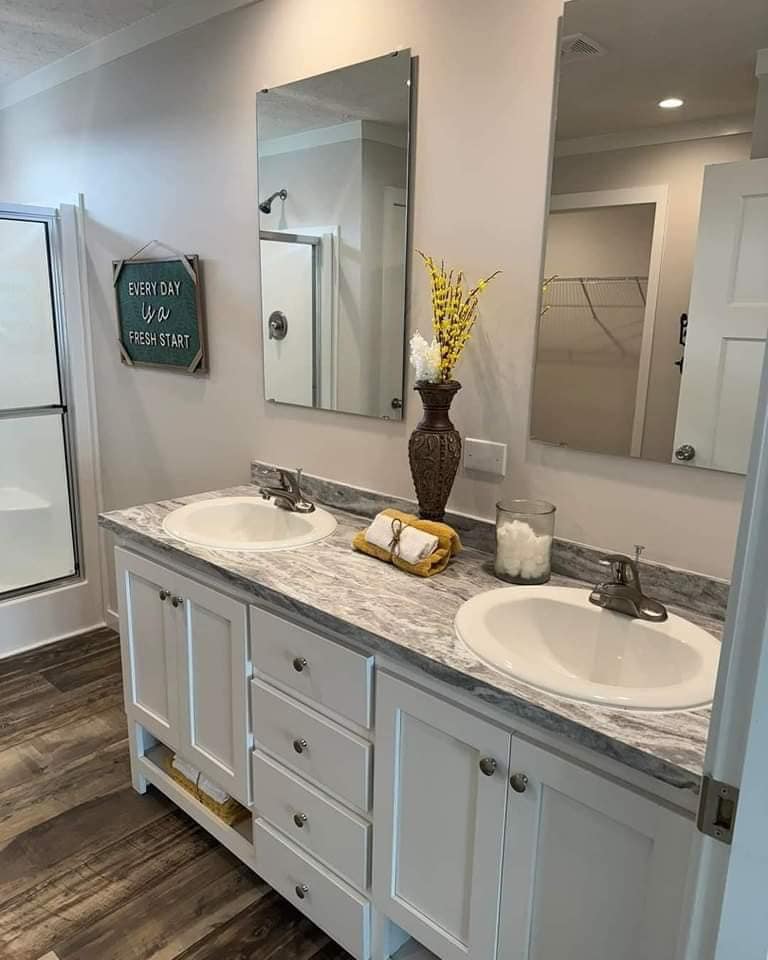 Modern bathroom with a double sink vanity, marble countertop, yellow flowers in a vase, and a motivational sign reading "Every Day is a Fresh Start."