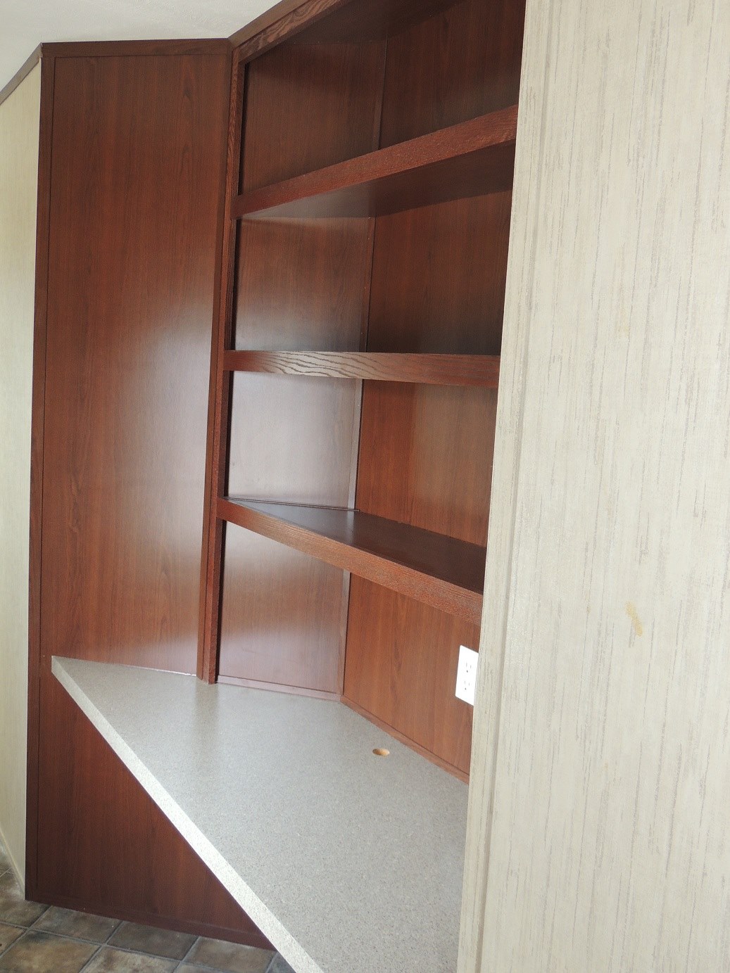 Wooden closet with shelves and a light gray countertop, creating a warm atmosphere. Beige walls and tiled floor provide a classic, neutral setting.