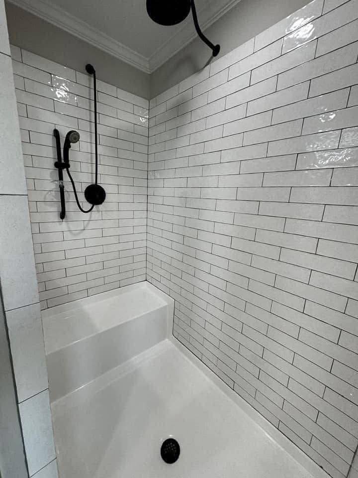 Modern shower with white subway tiles, black fixtures, and a built-in bench. Clean lines and minimalistic design create a sleek, contemporary look.