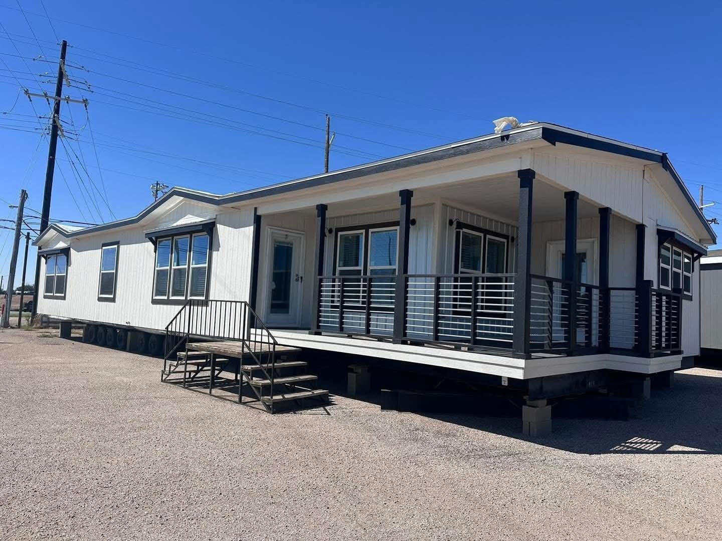 A mobile home featuring a porch and balcony, set against a clear blue sky.
