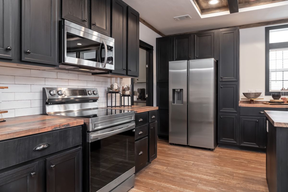 Modern kitchen with dark wooden cabinets, stainless steel appliances, and light wood flooring. Bright and inviting with a sleek, contemporary feel.