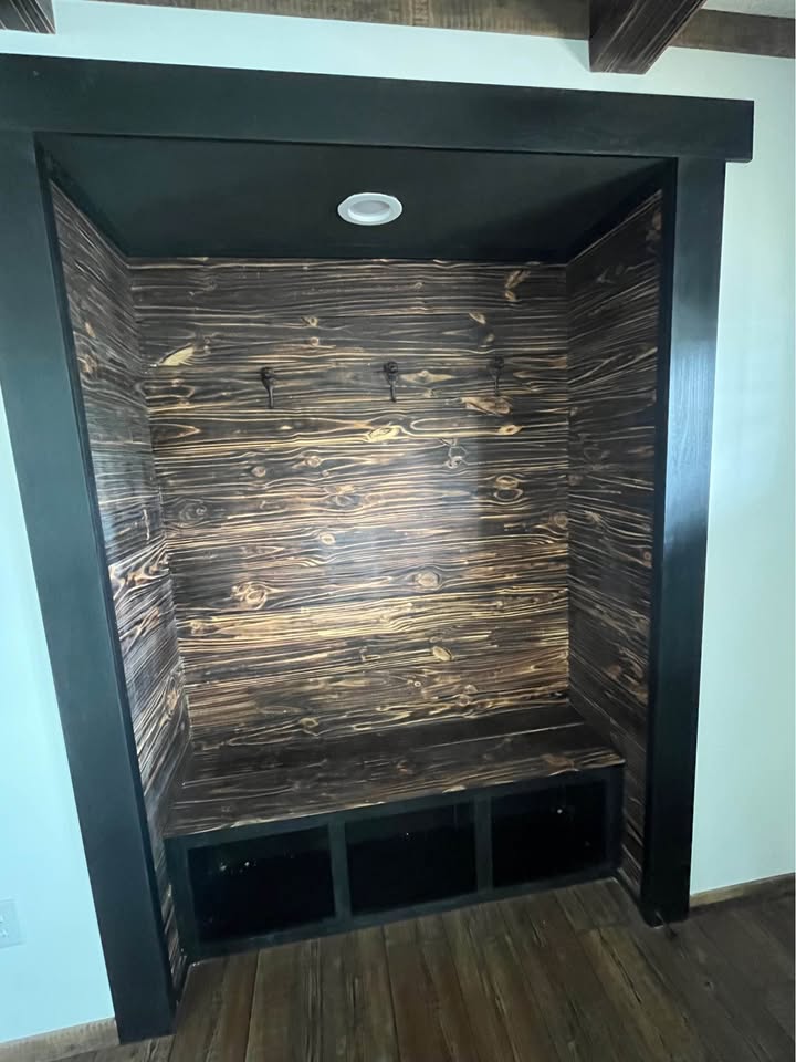 Dark wooden alcove with a rustic, charred finish. Features two hooks on the back panel and a bench with storage below, creating a cozy, inviting space.