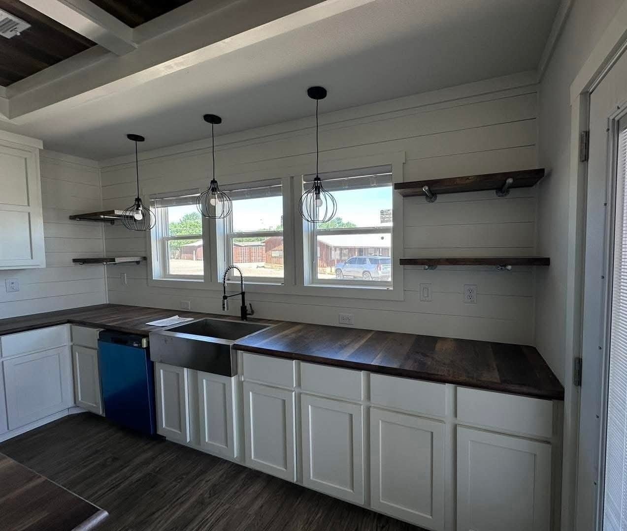A modern kitchen featuring white cabinets and warm wooden countertops, creating a bright and inviting atmosphere.