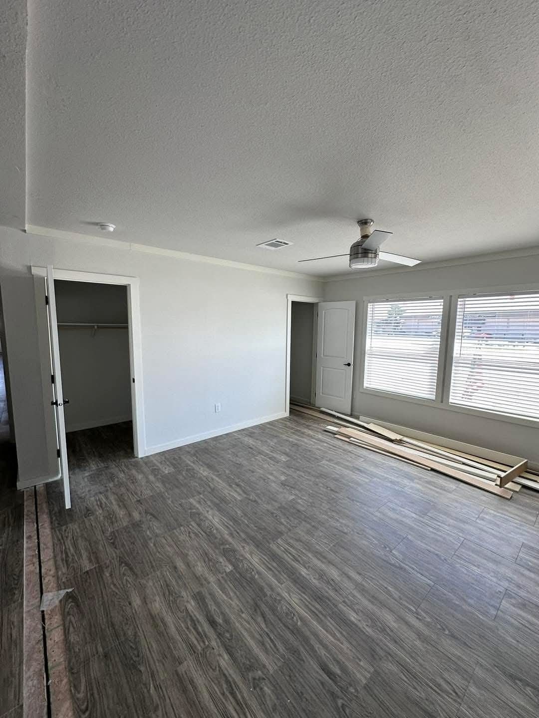  Empty room featuring wooden floors and a ceiling fan, creating a spacious and airy atmosphere.