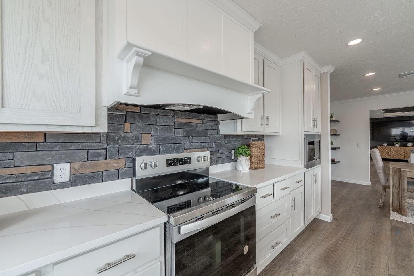 A spacious, modern kitchen and dining area with a wooden table and four chairs. Neutral tones, large windows, and sleek appliances create a cozy, inviting atmosphere.