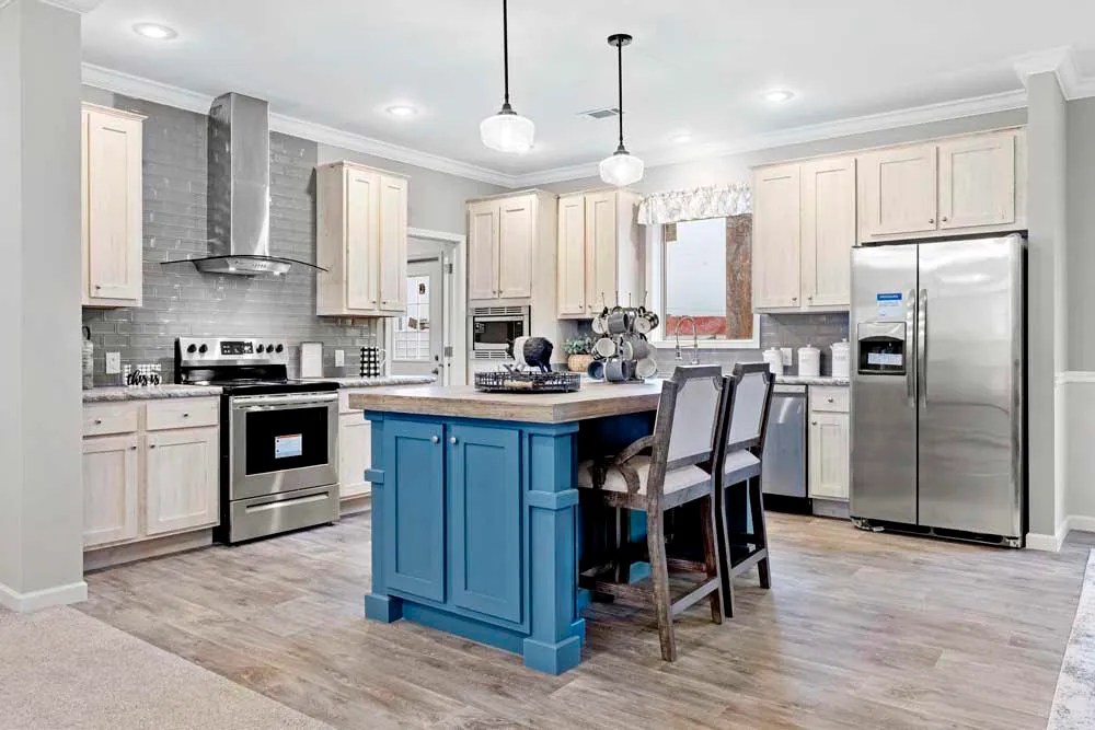 Modern kitchen with light wood cabinetry, stainless steel appliances, and a central island. The island is painted blue with two high chairs.