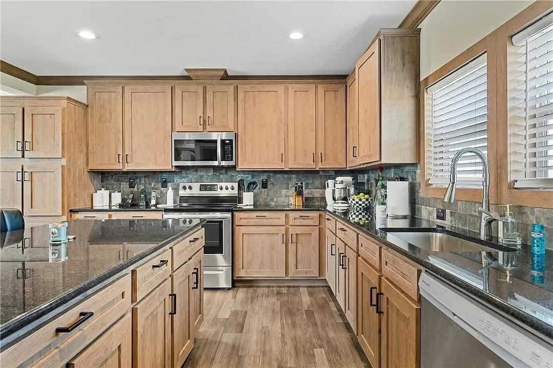 Modern kitchen with wooden cabinets, stainless steel appliances, and granite countertops. Bright lighting, hardwood floor, cozy and functional vibe.
