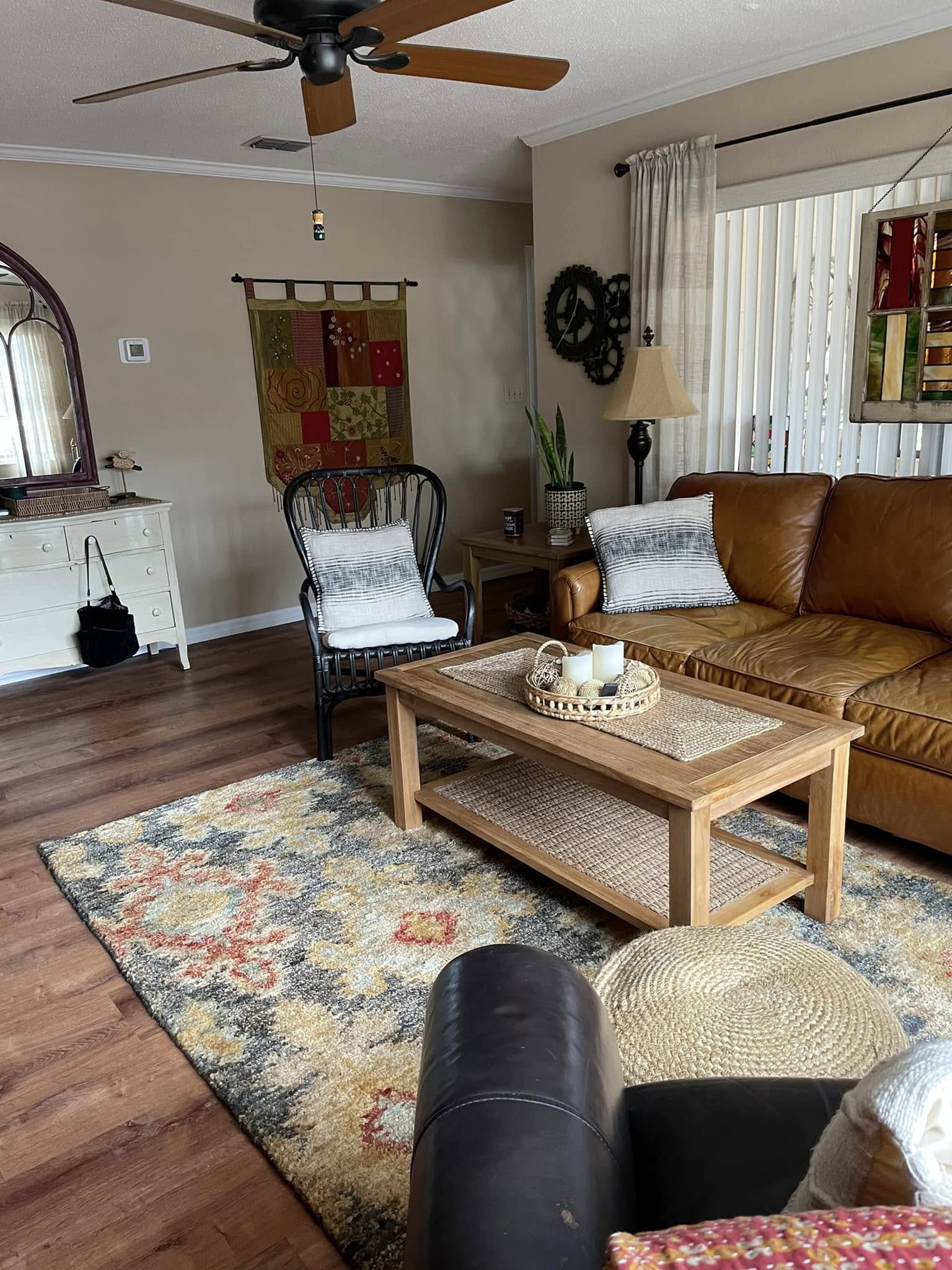Cozy living room with a brown leather sofa, wooden coffee table, and decorative rug. A white chair, wicker basket, and calming earth tones create a warm, inviting atmosphere.