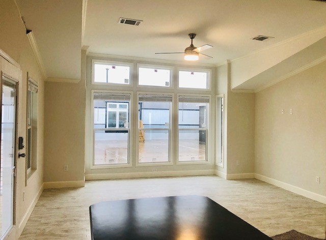 Spacious, modern room with light wood flooring, large windows, and ceiling fan. Bright and airy atmosphere with a minimalist design.