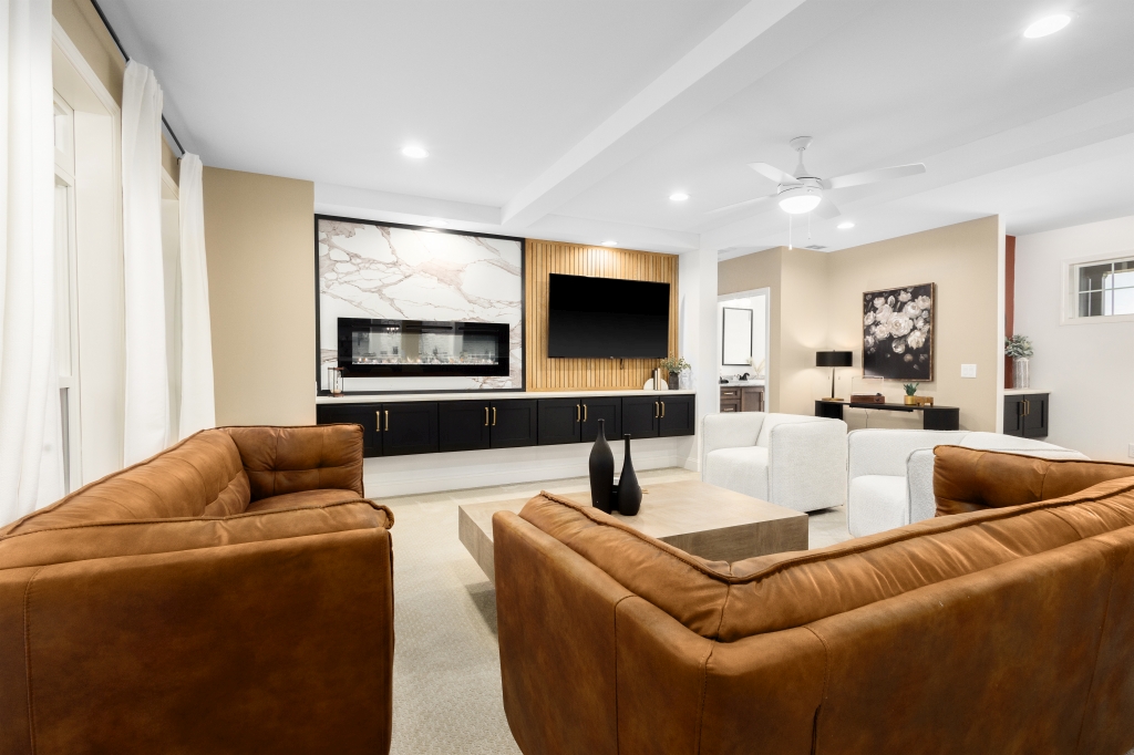 Modern living room with brown leather sofas, a sleek black entertainment unit, and a wall-mounted TV. Neutral tones and soft lighting create a cozy atmosphere.