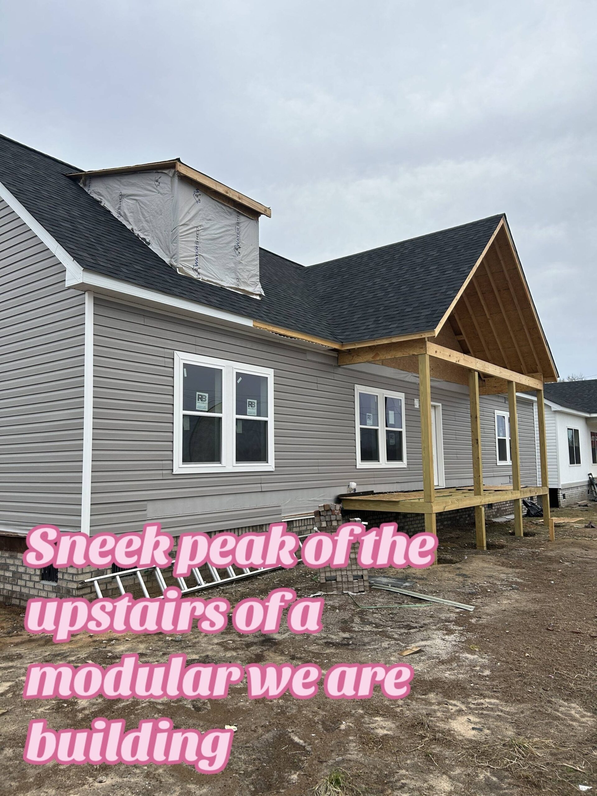 Gray modular home under construction with visible wooden framing and plastic-covered dormer. Overcast sky. Text overlay reads, "Sneek peak...modular we are building."