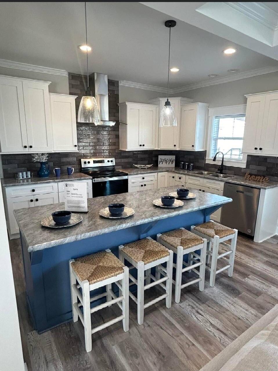 Modern kitchen with a blue island, four stools, and elegant lighting. White cabinets, stainless steel appliances, and a cozy, inviting atmosphere.