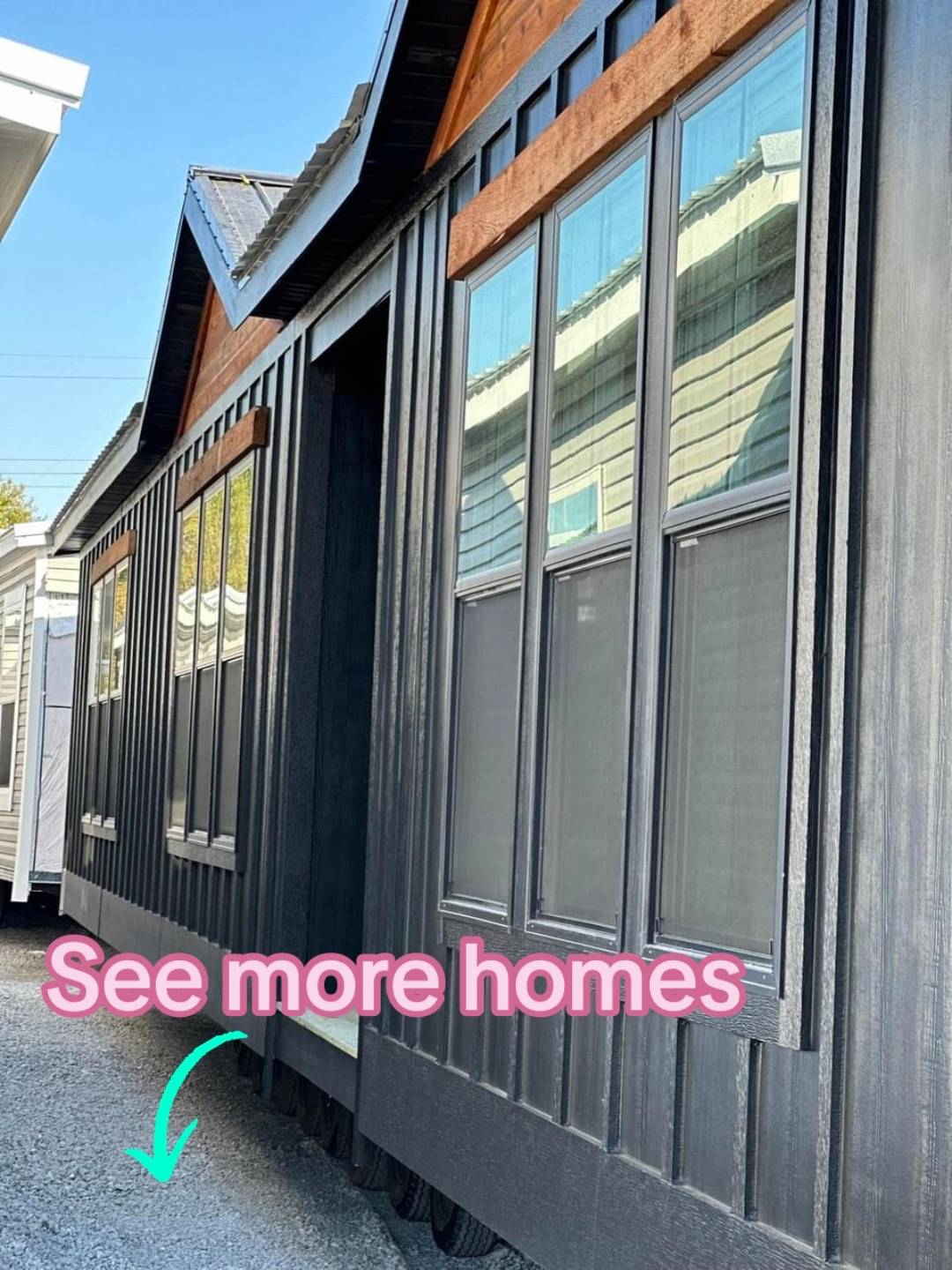Modern tiny home with dark exterior and large windows, aligned beside similar homes. Text overlay reads "See more homes" with a green arrow pointing down.