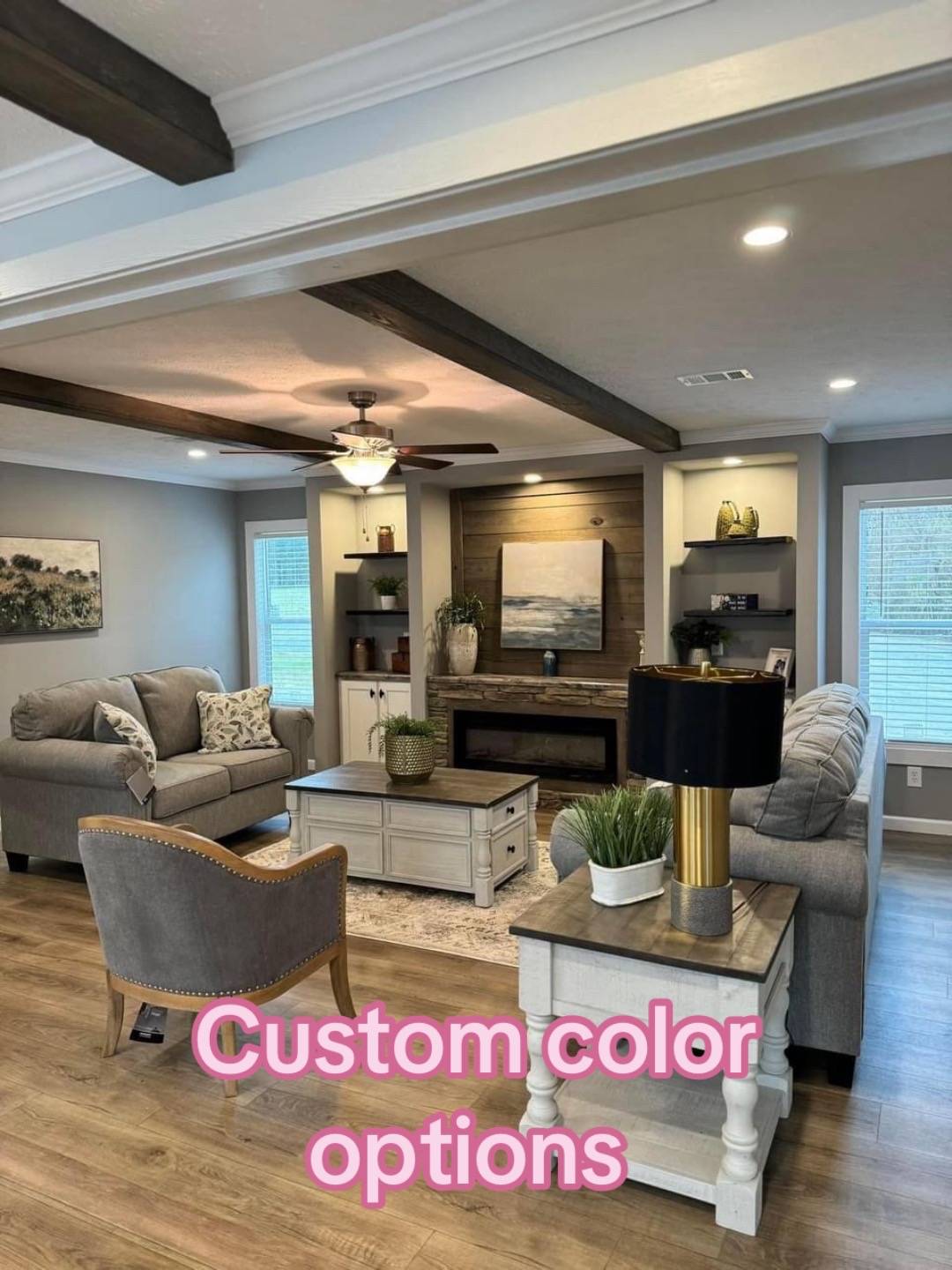 Modern living room with neutral tones, featuring gray couches, a fireplace, wooden beams, and decor plants. Text reads "Custom color options."