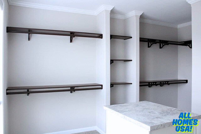 A minimalist walk-in closet with white walls and dark wooden shelves. An island countertop stands in the center. The space feels modern and organized. Image for illustrative purposes.