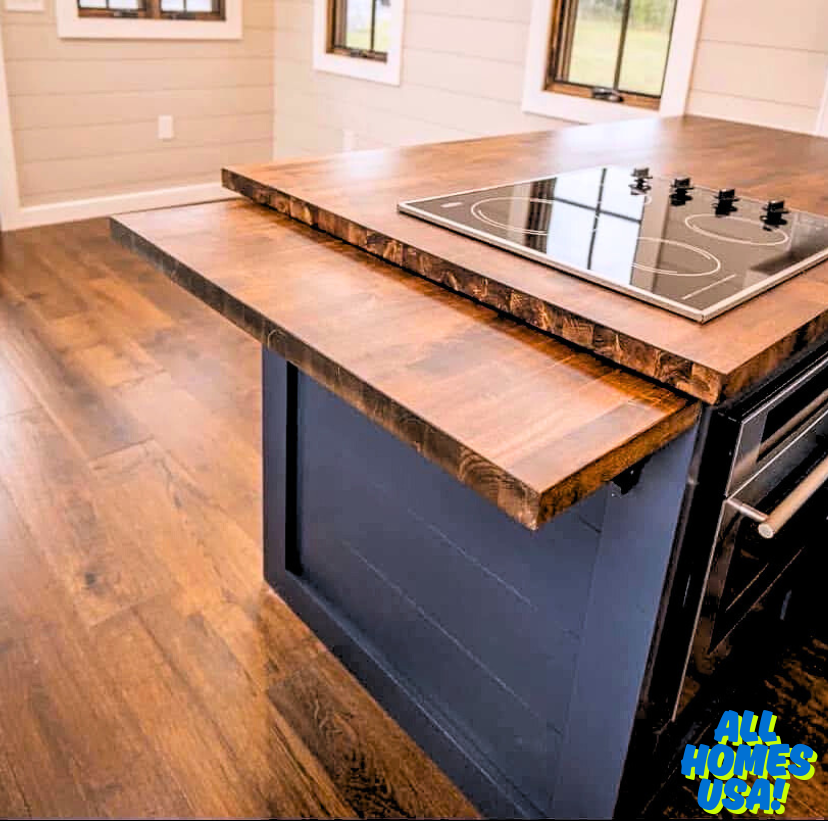 Modern kitchen with a dark wood island, fitted cooktop, and rich wood floor. The blue base adds contrast, creating a cozy, elegant atmosphere. Image for illustrative purposes.