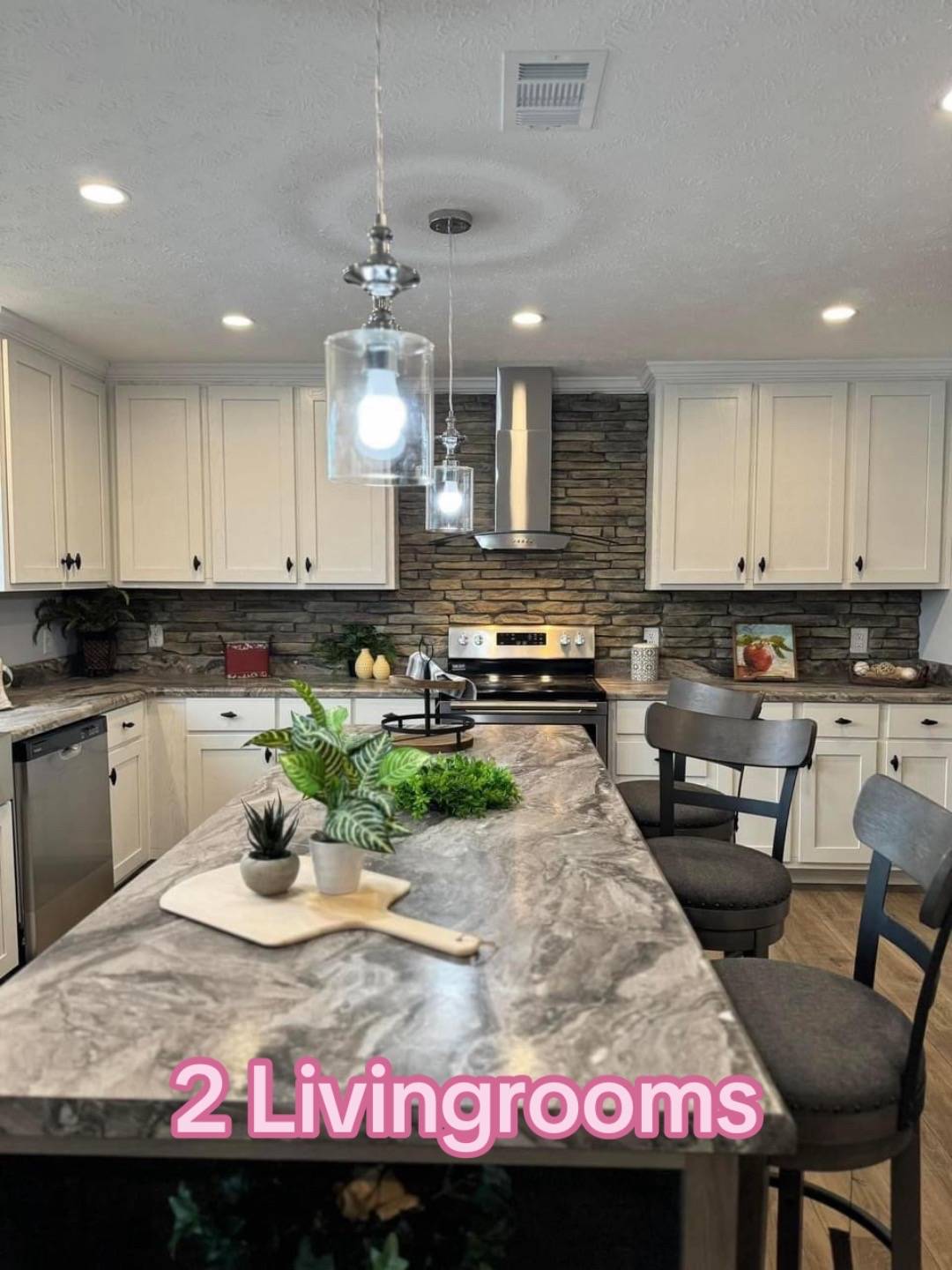 Modern kitchen with marble island and hanging lights. White cabinets, stone backsplash, stainless steel appliances, and "2 Livingrooms" text overlay.