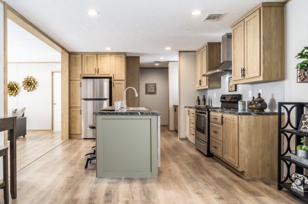 Spacious kitchen with light wood cabinets, stainless steel appliances, and a central island with a modern faucet. Warm, inviting atmosphere.