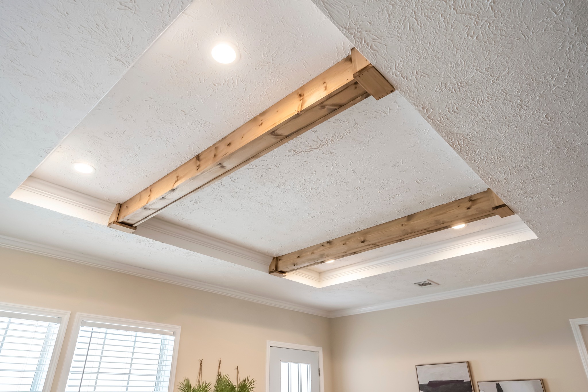 Ceiling with wood beams and recessed lights, creating a warm and cozy atmosphere. Textured white surface and natural tones enhance the elegant decor.