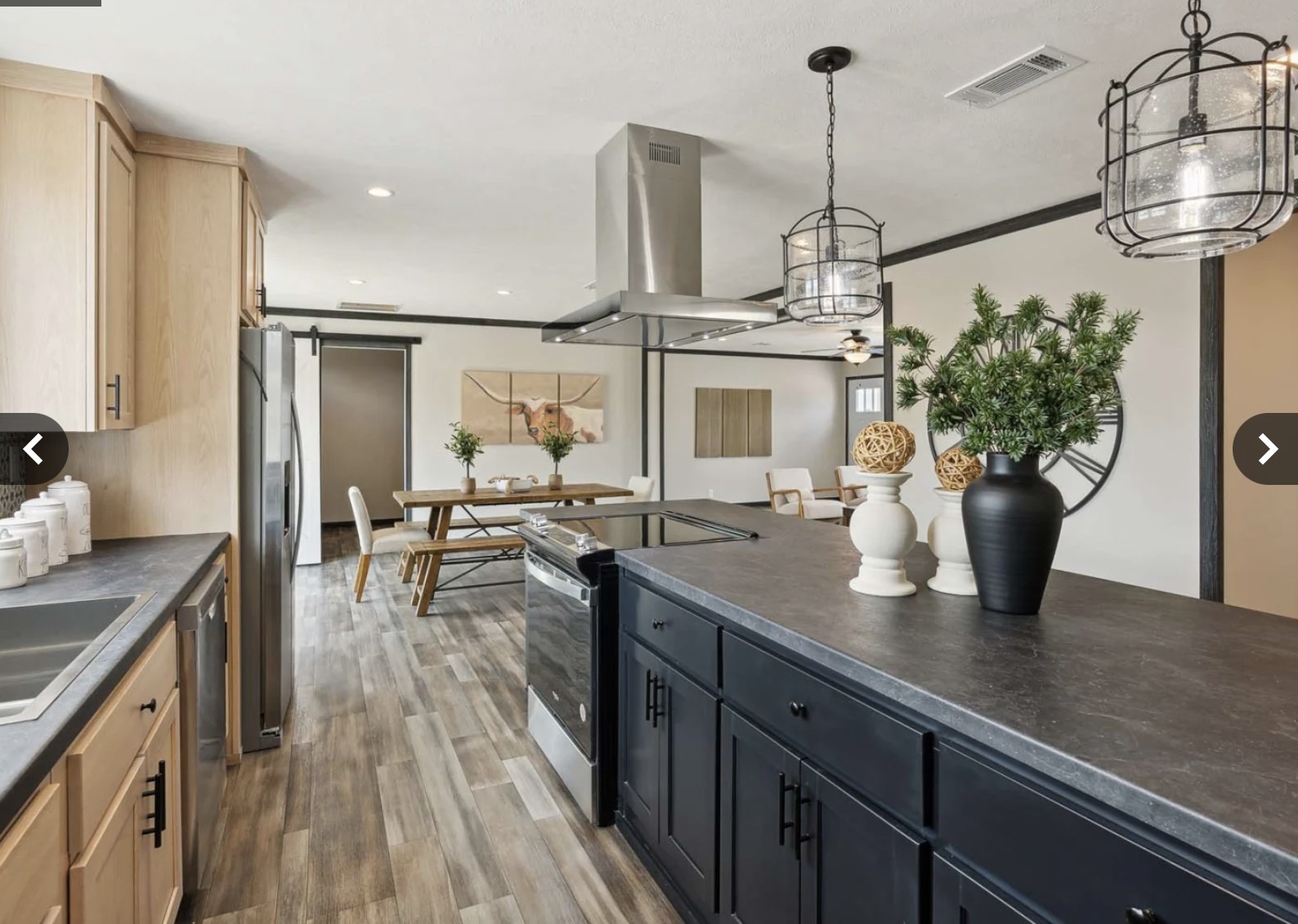 Modern kitchen and dining area with hardwood floors. Black island, pendant lights, stainless steel appliances, and chic decor create a cozy, elegant ambiance.