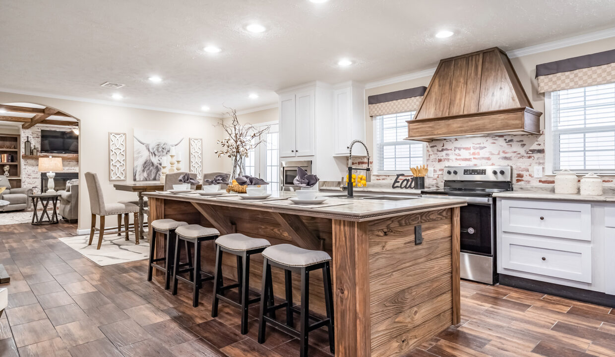 Spacious kitchen with a rustic wooden island, modern white cabinets, and stone backsplash. Bar stools line the island, exuding warmth and elegance.