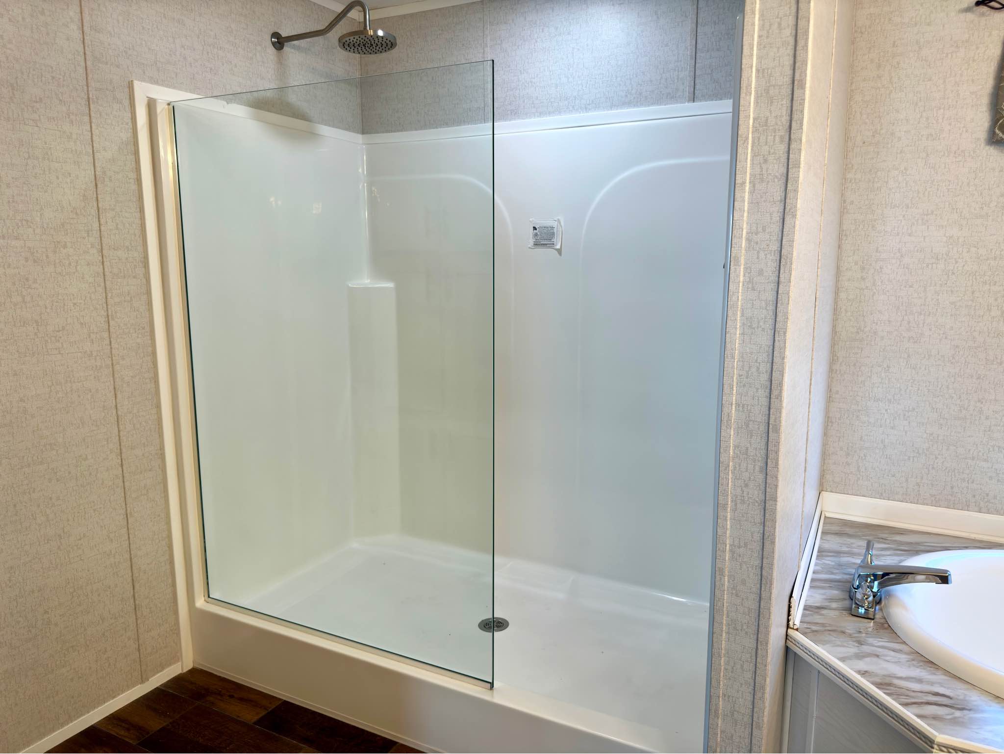 Modern bathroom with a glass-enclosed shower featuring a sleek rainfall showerhead. Adjacent, a marble-topped sink is visible, creating a clean and serene atmosphere.