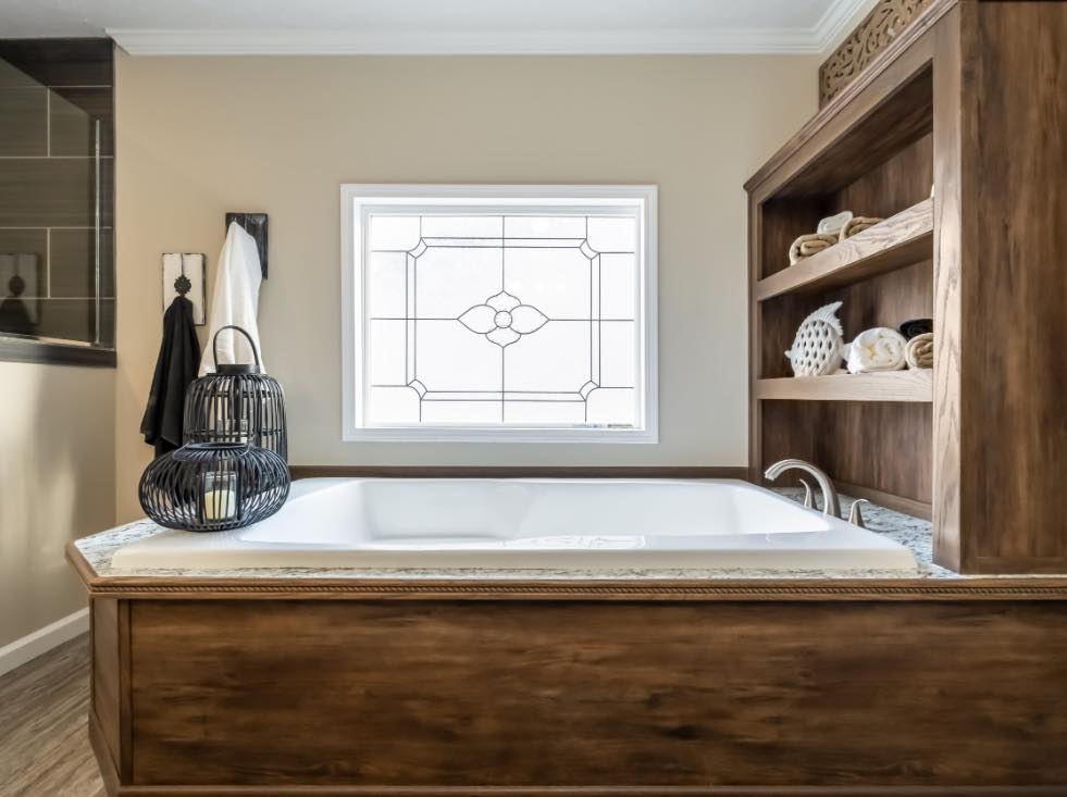 Luxurious bathroom with a wooden-framed bathtub, decorative shelving, and a stained glass window. Soft, neutral tones create a calming atmosphere.