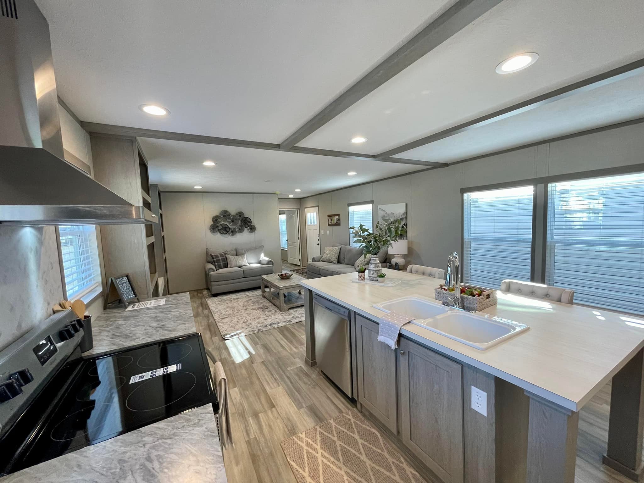 Modern open-concept kitchen and living room with neutral tones. Features a marble countertop island, stainless steel appliances, and cozy seating area. Bright, inviting ambiance.