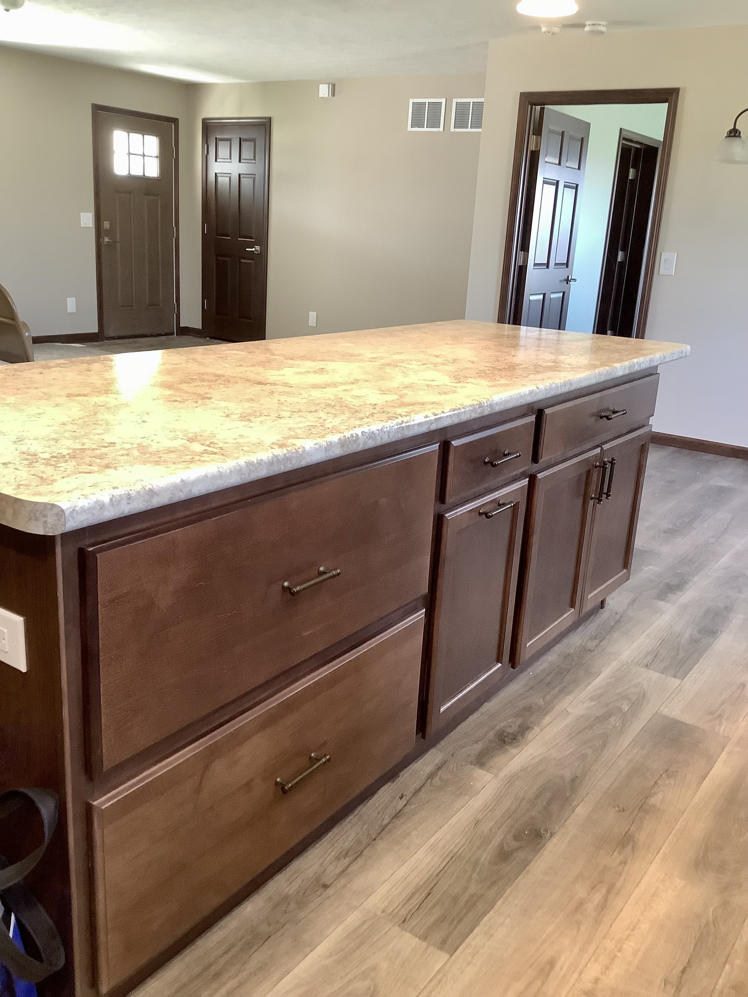 Kitchen with a wooden island featuring dark cabinets and a light countertop. Sunlight illuminates the space, creating a warm and inviting atmosphere.