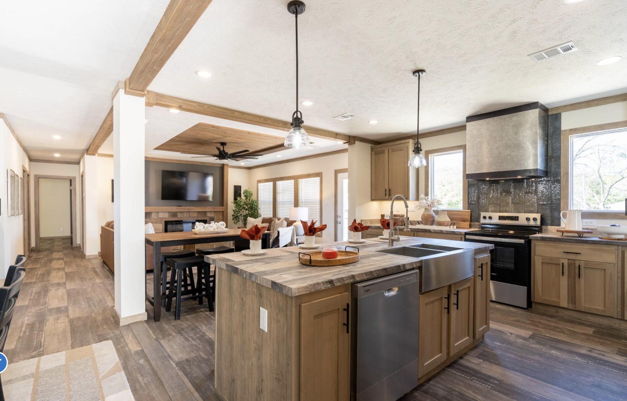 Modern open-concept kitchen and living area with wood accents. Features pendant lights, a central island, and a cozy dining space. Bright and inviting atmosphere.
