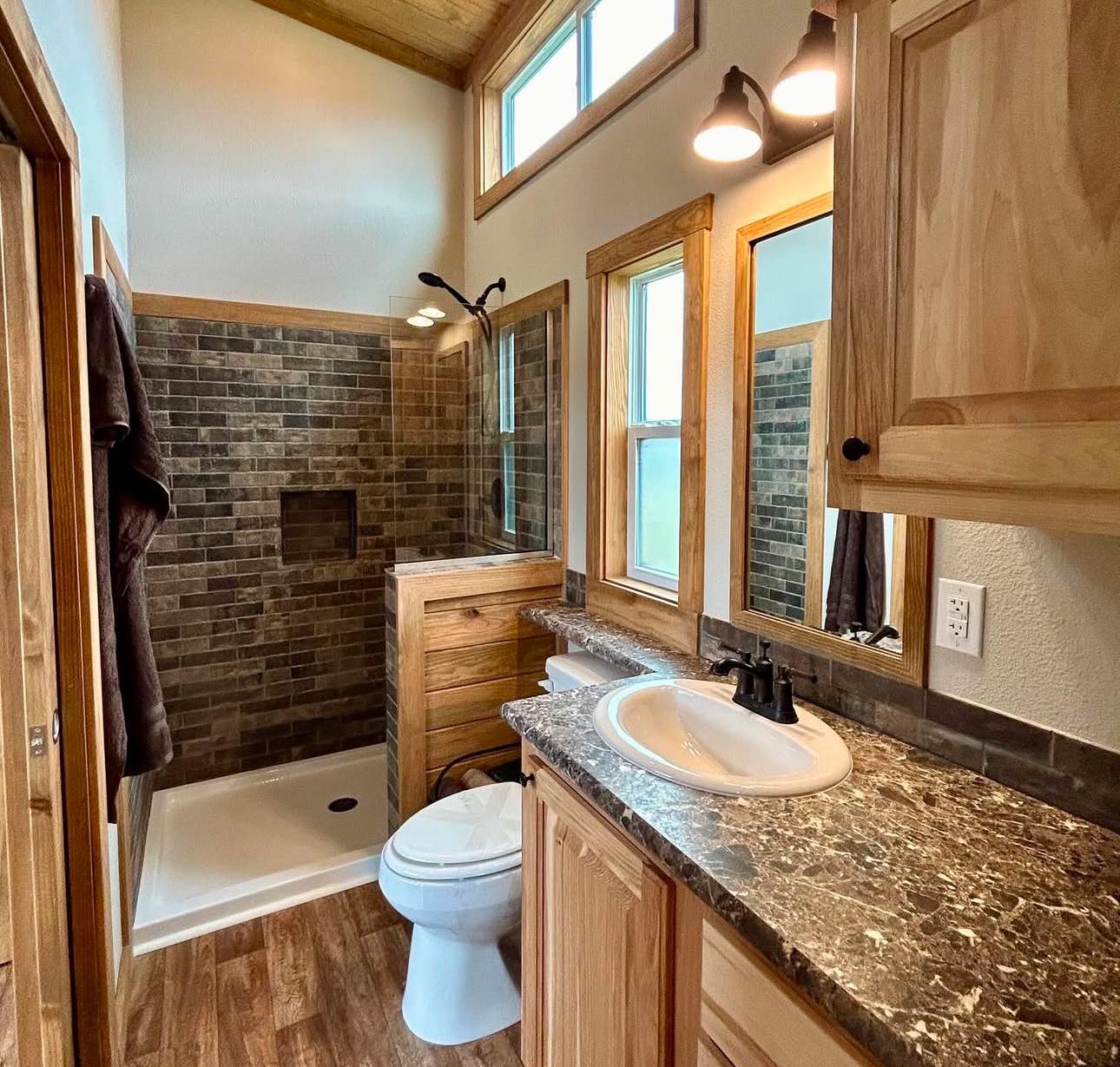 Cozy bathroom with rustic wood cabinetry, a marble countertop, and a stone tile shower. Warm lighting, earthy tones, and a serene, inviting atmosphere.