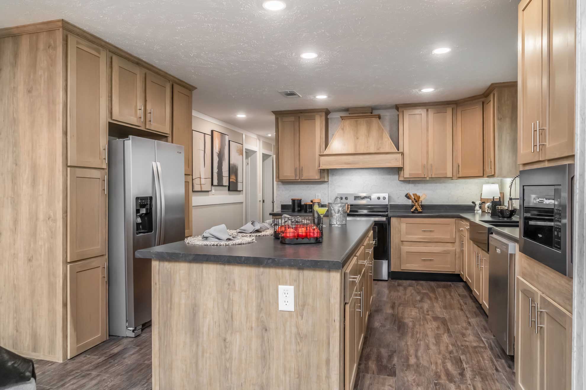 Spacious kitchen with wooden cabinets, center island, stainless steel appliances, and recessed lighting. Warm tones create a cozy ambiance.