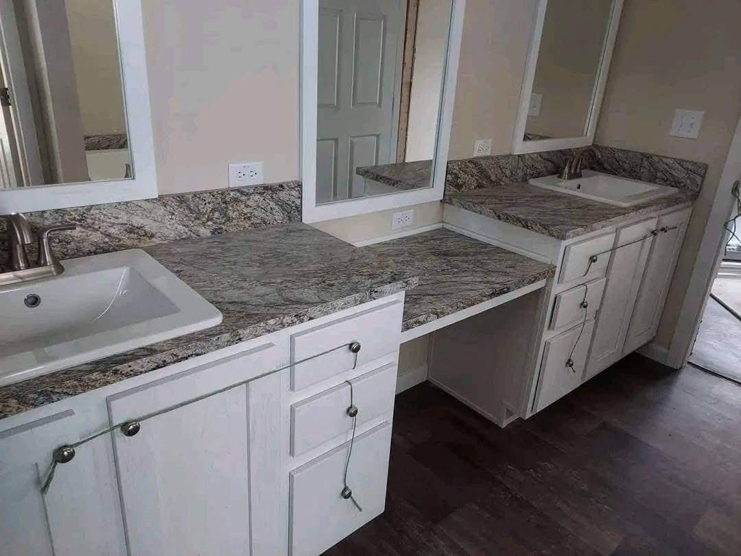 A bathroom vanity with marble countertops and two white sinks. Mirrors are above each sink, with two sets of cabinets below, connected by a flat surface.