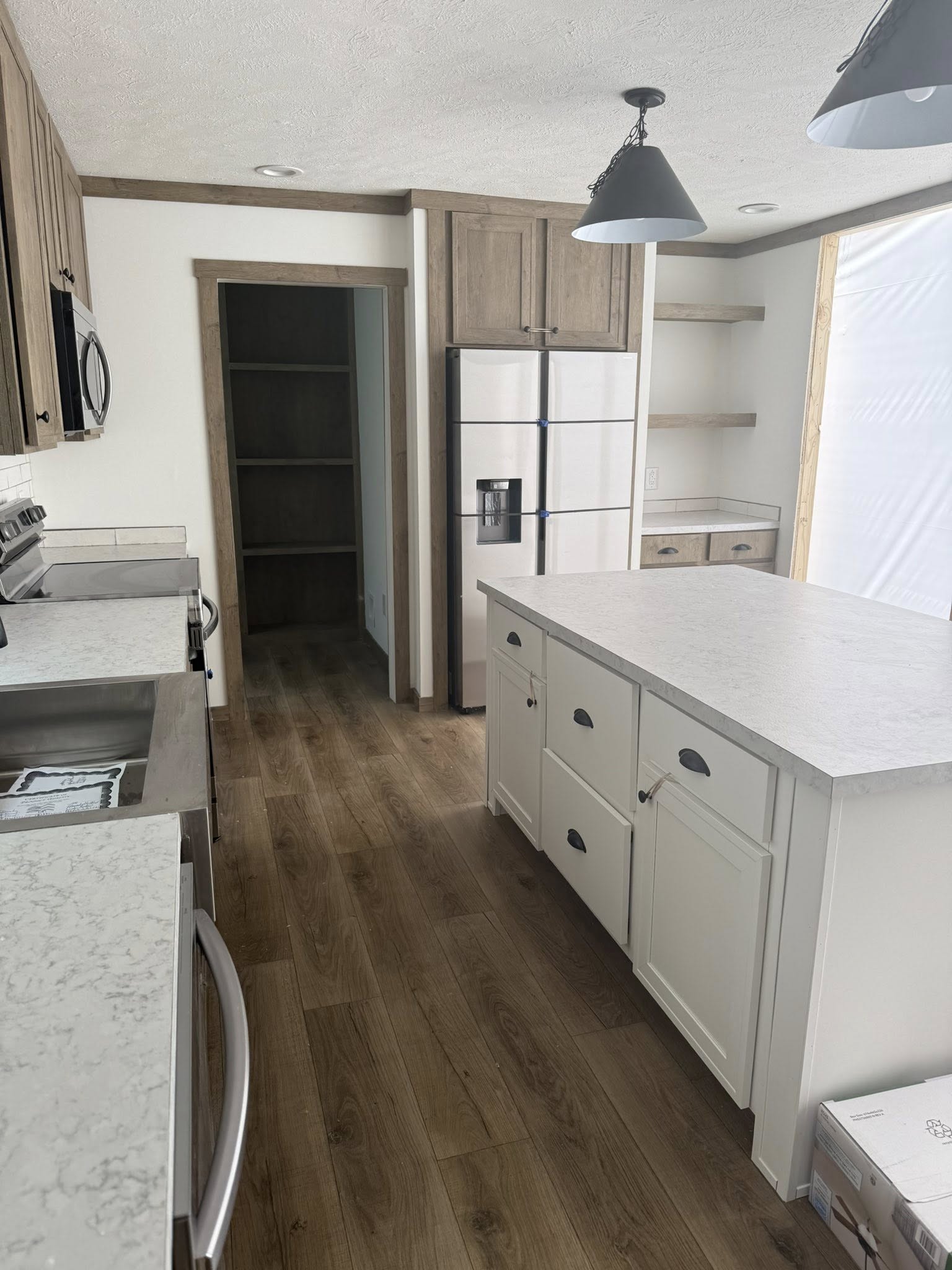 Modern kitchen with white cabinets, wood accents, and a central island. Stainless steel appliances, wood flooring, and pendant lights create a sleek look.