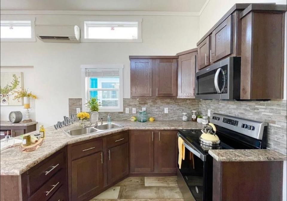 Modern kitchen with dark wood cabinets, granite countertops, and stainless steel appliances. Bright with natural light from windows, cozy and welcoming.