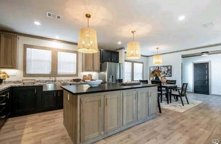 Modern kitchen and dining area with light wood floors and accents. Central island with pendant lights, stainless steel appliances, and cozy dining setup.