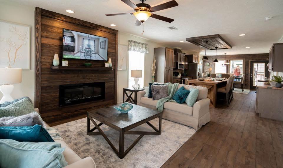 A cozy, open-concept living room with a beige couch and teal pillows, wooden coffee table, and fireplace. Warm lighting and decor create an inviting atmosphere.