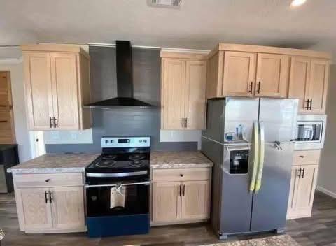 Modern kitchen with light wood cabinets, stainless steel appliances, and a black range hood. The setting is clean and organized, conveying warmth.
