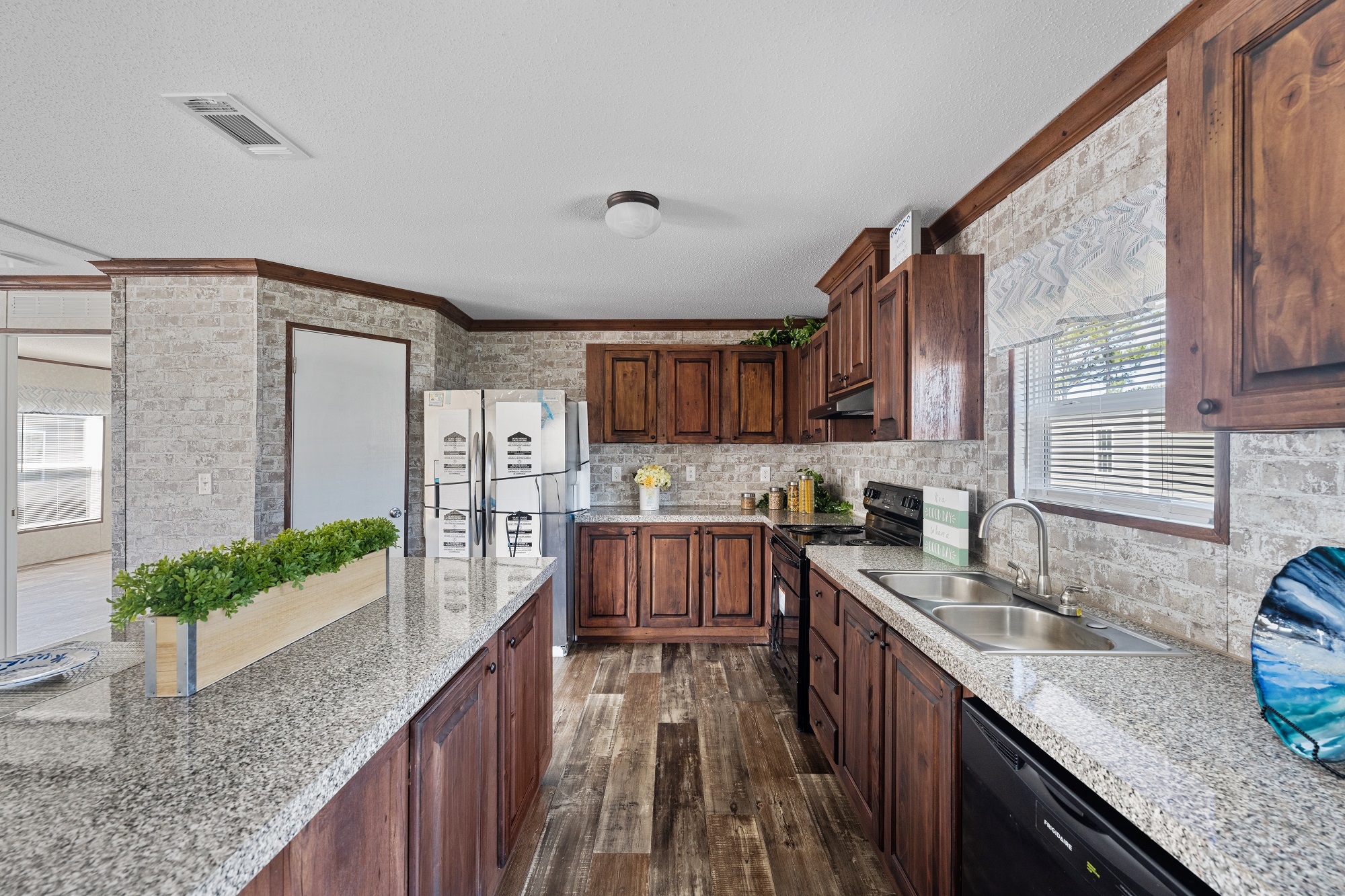 Modern kitchen with rustic charm features wooden cabinets, granite countertops, and stainless steel appliances. A green plant adds freshness and warmth.