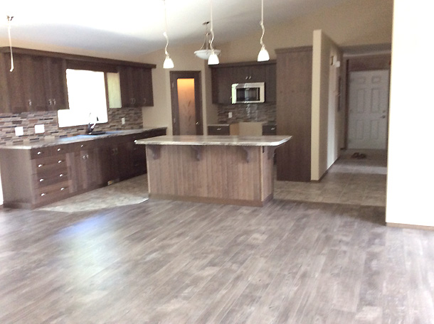 Spacious modern kitchen with dark wood cabinets, granite island, pendant lights, stainless steel appliances, and a tiled backsplash. Cozy and inviting.