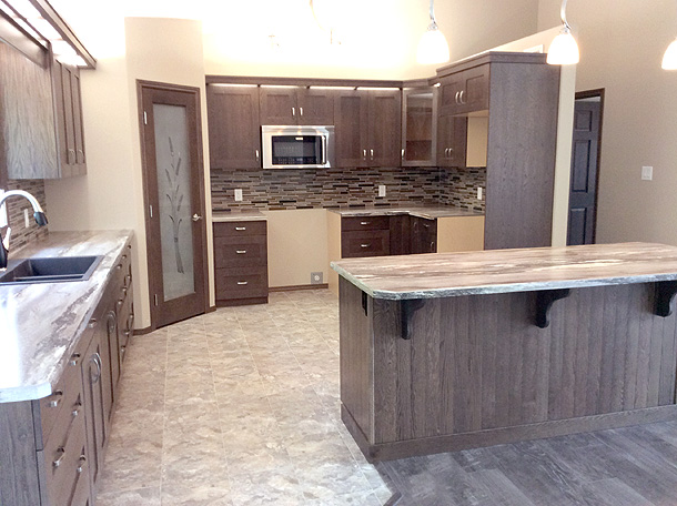 Spacious kitchen with dark wooden cabinets, a central island, granite countertops, and a stainless steel microwave. Soft lighting creates a warm ambiance.