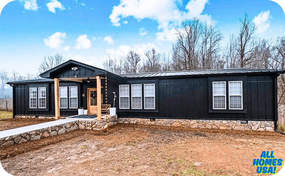 Front view of a modern, black-clad house with wooden accents, surrounded by sparse trees and clear blue skies. Image for illustrative purpose.